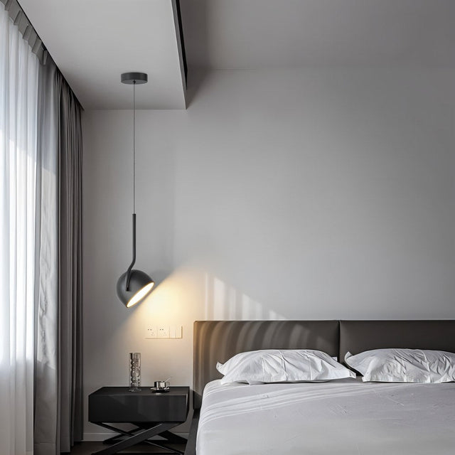  "A black, curved iron pendant light with a dome-shaped shade hangs in a modern bedroom with dark accents, providing focused illumination over a nightstand."