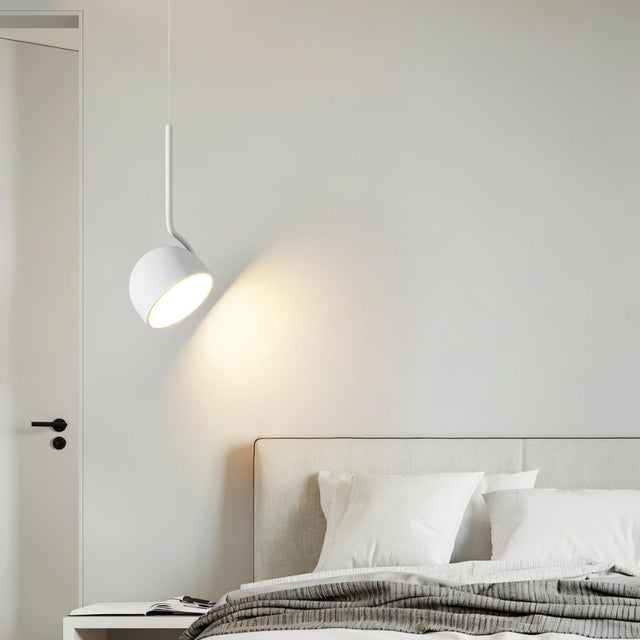 "A white, curved iron pendant light with a dome-shaped shade hangs in a minimalist bedroom, providing focused light over a bed."