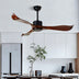 Modern ceiling fan with dark motor and curved walnut wood blades mounted in minimalist kitchen above countertop.