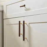 "Modern wooden knobs and pull handles with brass accents on white kitchen cabinets."