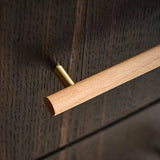 "Close-up of a wooden drawer pull with brass detailing on a dark wood surface."