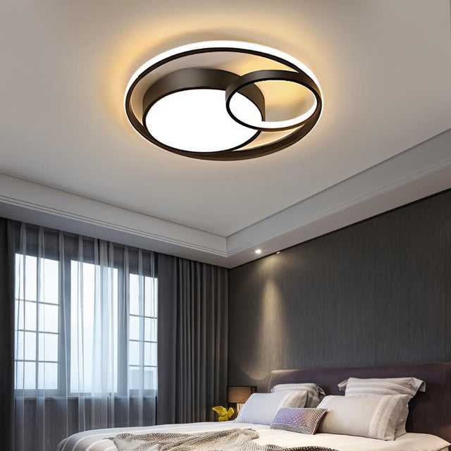 "A modern black ceiling light with interlocking rings in a bedroom."