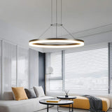 "A modern ring chandelier in a living room with a white sofa and yellow ottoman."
