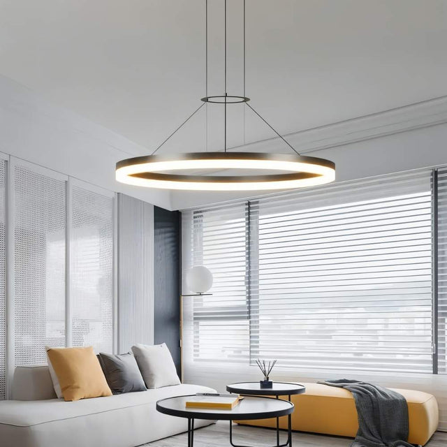 "A modern ring chandelier in a living room with a white sofa and yellow ottoman."