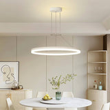 "A modern white ring chandelier in a dining room with a round table and white chairs."