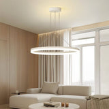"A modern white ring chandelier in a living room with a white sofa and round table."