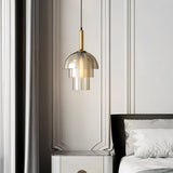  "Modern pendant light with layered smoked glass shade and metallic accent in a bedroom setting."