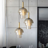   "Three modern pendant lights with layered smoked glass shades and metallic accents over a dining table in a contemporary dining room."