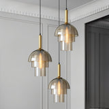  "Three modern pendant lights with layered smoked glass shades and metallic accents in a contemporary living room."