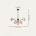Black metal chandelier with five amber glass globe shades on a beige background.