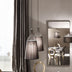 Two black fabric pendant lights with metal wireframe tops hang above a modern table reflected in a rounded mirror.