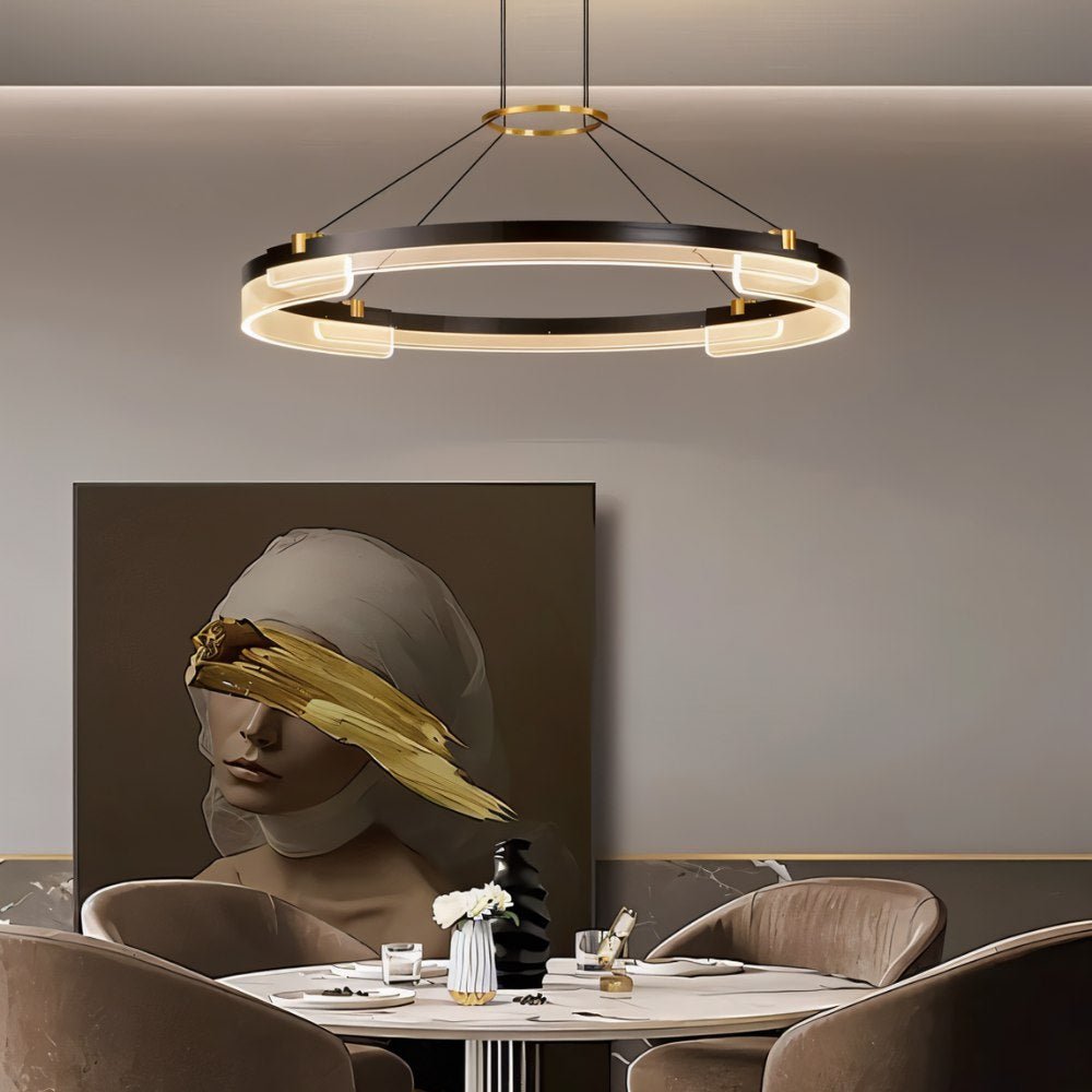 "Black and gold Capli chandelier with dual aluminum rings and acrylic diffusers, hanging above a dining table with a modern painting."