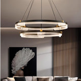 "Black and gold Capli chandelier with dual aluminum rings and acrylic diffusers, hanging above a living room with a modern art piece."