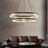 "Black and gold Capli chandelier with dual aluminum rings and acrylic diffusers, hanging above a living room with a brown leather sofa."