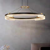 "Black and gold Capli chandelier with a single aluminum ring and acrylic diffusers, hanging in a room with a grey wall."
