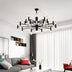 Black and natural wood modern chandelier with multiple candle-style lights suspended in a contemporary living room.