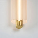 "Close-up of a minimalist pendant light showing the frosted acrylic cylinder and brass details, with a warm light glowing from within."
