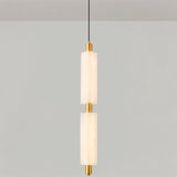 "A double-tiered, minimalist pendant light with two frosted acrylic cylinders and brass accents, hanging from a thin black cord."