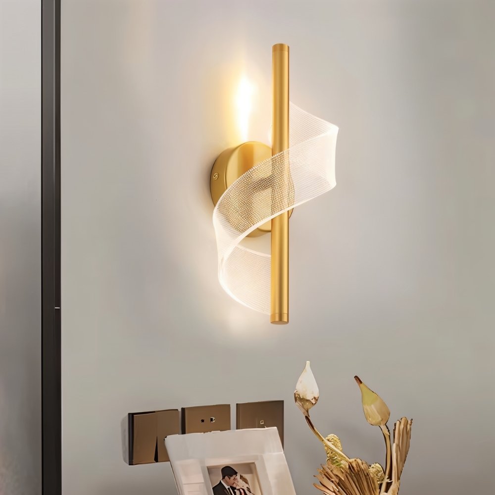 "Modern wall lamp with a spiral acrylic diffuser and a sleek gold metal frame, emitting a warm, ambient light."