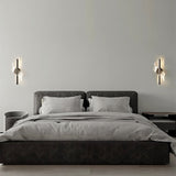 "Pair of modern sculptural wall lamps with spiral acrylic diffusers flanking a bed in a contemporary bedroom."