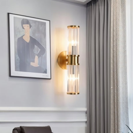 "A modern wall lamp with clear glass panels in a living room setting, mounted on the wall next to a painting and curtains."