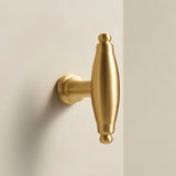 "Polished brass cabinet knob with an elongated, sculptural design."