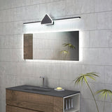 "A modern black and white wall lamp with a geometric centerpiece and streamlined bar, mounted above a bathroom vanity mirror with integrated lighting, in a contemporary bathroom with gray tiled walls."