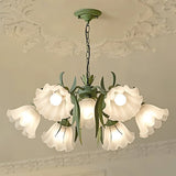 "Close-up of a floral chandelier with curved arms and frosted glass shades, hanging from a decorative white ceiling."