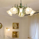 "A close-up of a floral chandelier with curved iron stems and frosted glass flower shades, showcasing its intricate details."