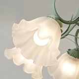 "Close-up detail of a frosted glass shade on a floral chandelier, shaped like a blooming flower and softly diffusing light."