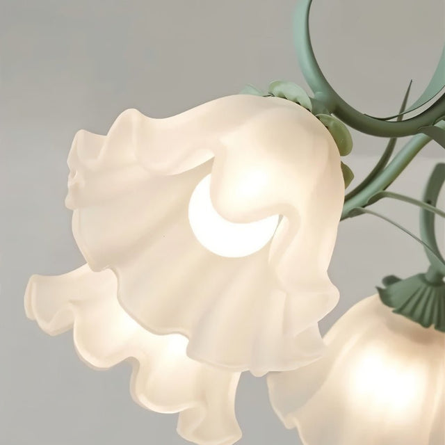 "Close-up detail of a frosted glass shade on a floral chandelier, shaped like a blooming flower and softly diffusing light."