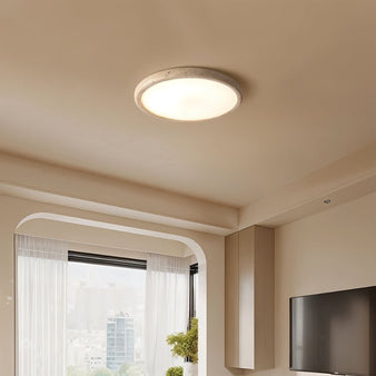 "A modern travertine flush mount ceiling light with a circular design, providing ambient lighting in a contemporary living room."