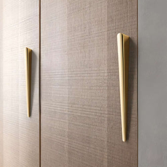 "Two sleek, tapered zinc alloy pull bars with a geometric profile in a gold finish on a modern wooden cabinet."