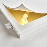 "A close-up of a trimless wall light showing the bulb and curved design detail, casting a warm light."