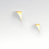 "Two curved trimless wall lights casting a warm glow on a white wall, showcasing a minimalist design."