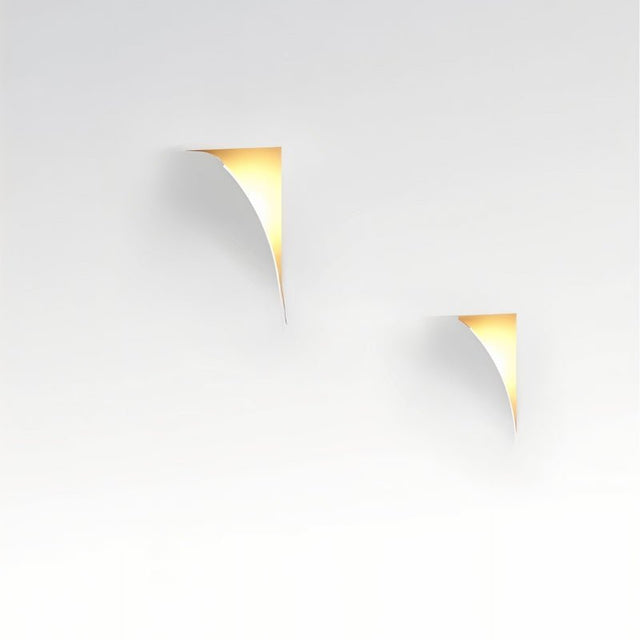 "Two curved trimless wall lights casting a warm glow on a white wall, showcasing a minimalist design."