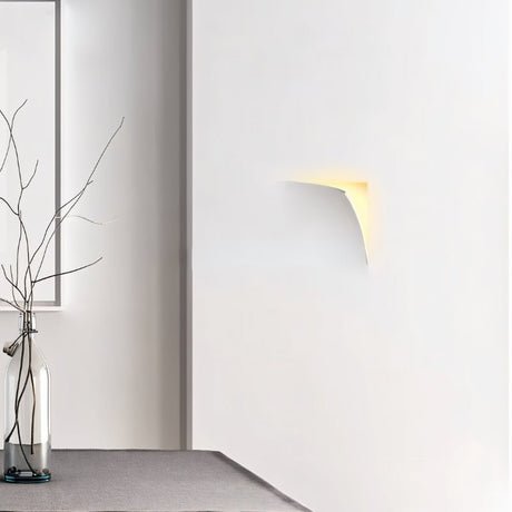"A recessed trimless wall light casting a soft glow on a white wall in a modern interior setting."