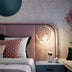 Gold crescent moon pendant light with astronaut figurine, illuminated above a modern bedroom nightstand.