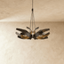 Black and gold multi-petal pendant light with warm interior finish suspended above dining table in modern interior setting.