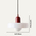 Red and white modern pendant light with cylindrical shade and black cord on neutral background.