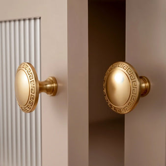 "Brass cabinet knobs with Grecian-inspired patterns on cabinet doors."