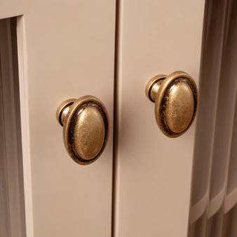 "Brass cabinet knobs on a light-colored cabinet, showcasing a vintage aesthetic."