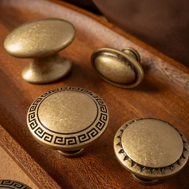 "Elegant brass cabinet knobs with intricate detailing, including Grecian-inspired patterns and textured surfaces."