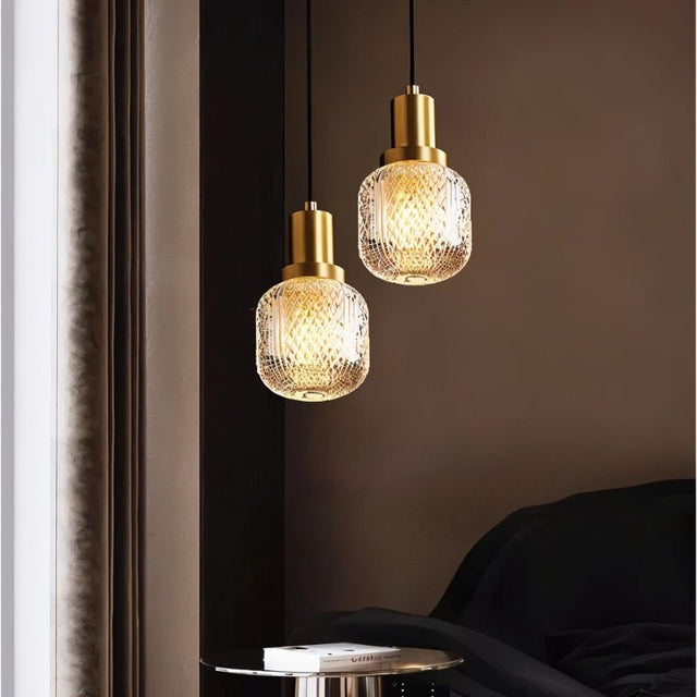 "Pair of modern pendant lights with brass bases and patterned glass shades, creating a warm and inviting ambiance in a contemporary bedroom setting."