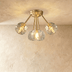 Gold flush mount ceiling light with seven textured crystal glass shades, lifestyle setting with white walls and gray curtains