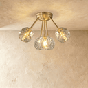 Gold flush mount ceiling light with seven textured crystal glass shades, lifestyle setting with white walls and gray curtains