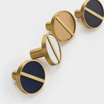 "Close-up of circular brass and leather cabinet knobs, showcasing the contrasting materials and detailed craftsmanship."