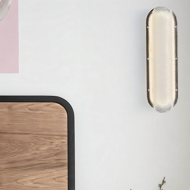 "Modern elongated wall lamp with a textured acrylic diffuser, mounted on a wall next to a bed."