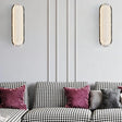 "Pair of modern elongated wall lamps with textured acrylic diffusers, mounted on a wall above a sofa in a contemporary living room."