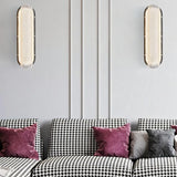 "Pair of modern elongated wall lamps with textured acrylic diffusers, mounted on a wall above a sofa in a contemporary living room."